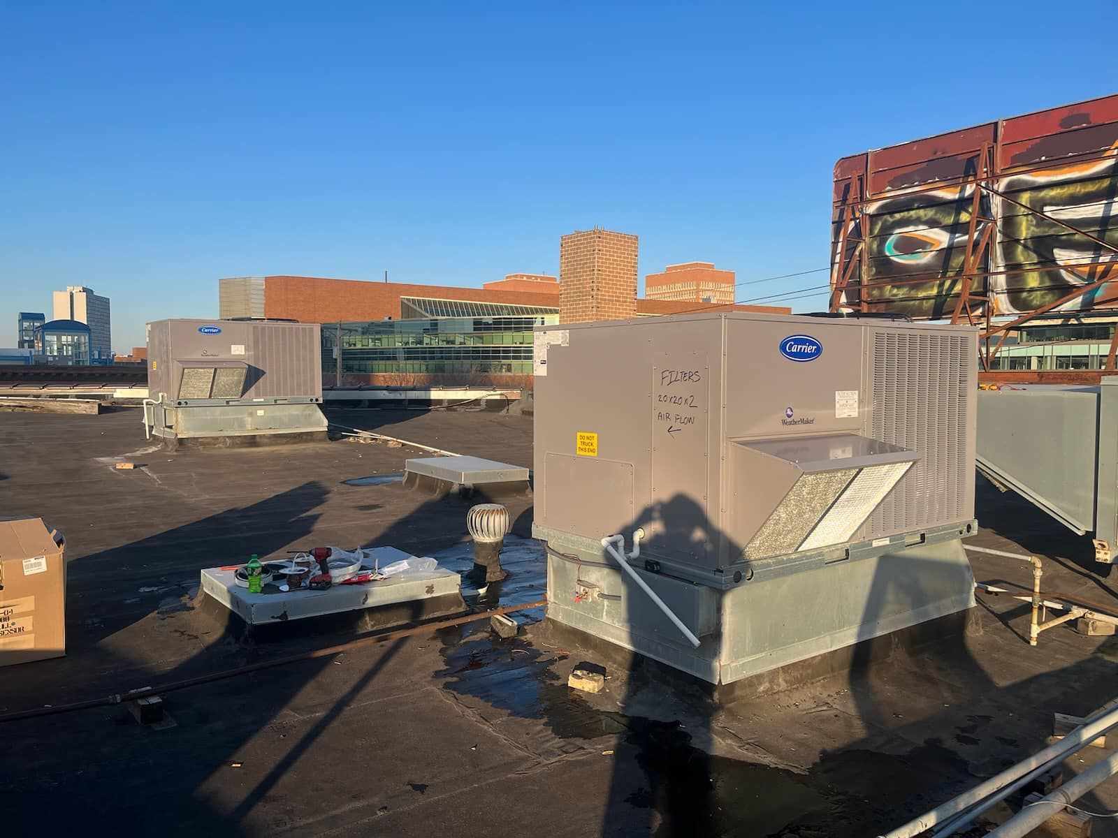 Rooftop with HVAC units and surrounding buildings under a clear sky.
