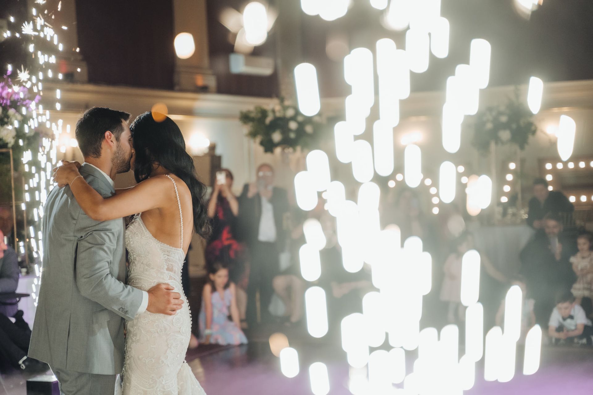 A bride and groom are kissing during their first dance at their wedding reception.