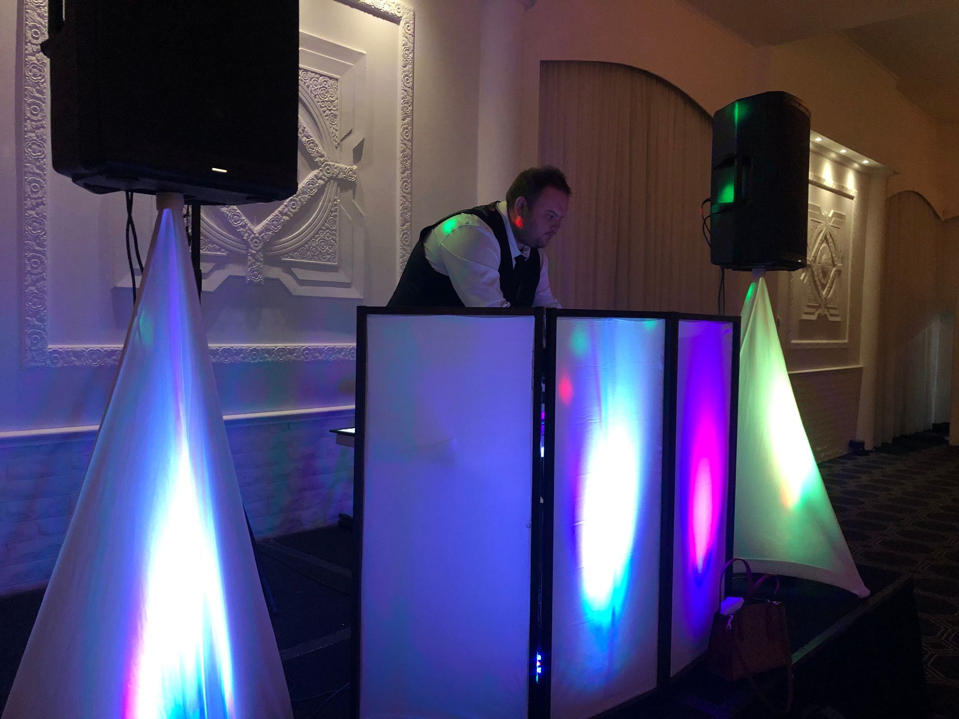 A man is standing in front of a dj booth at a party.