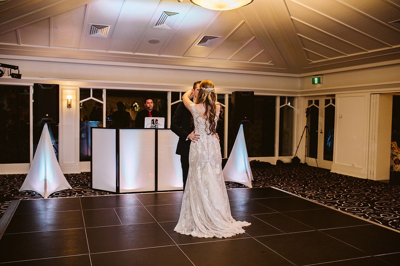 A bride and groom are dancing on a dance floor in front of a dj.