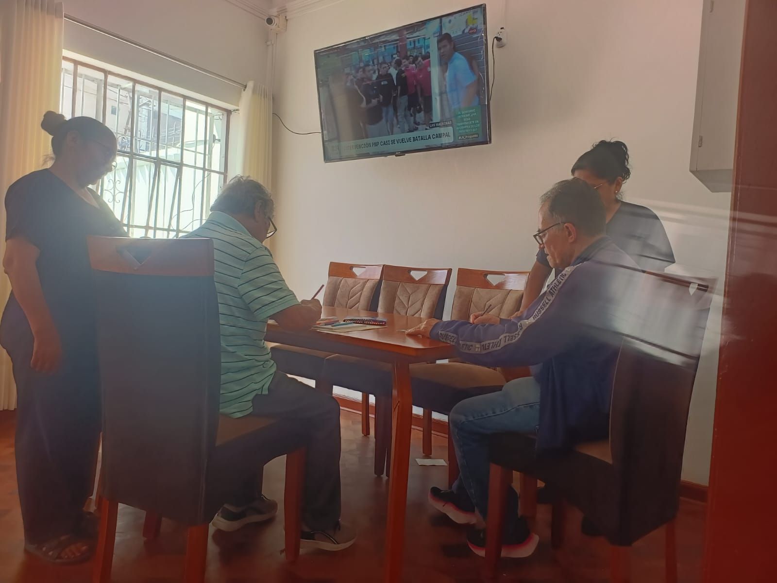 Equipo sanitario hablando con un paciente sentado en una luminosa sala de consulta.