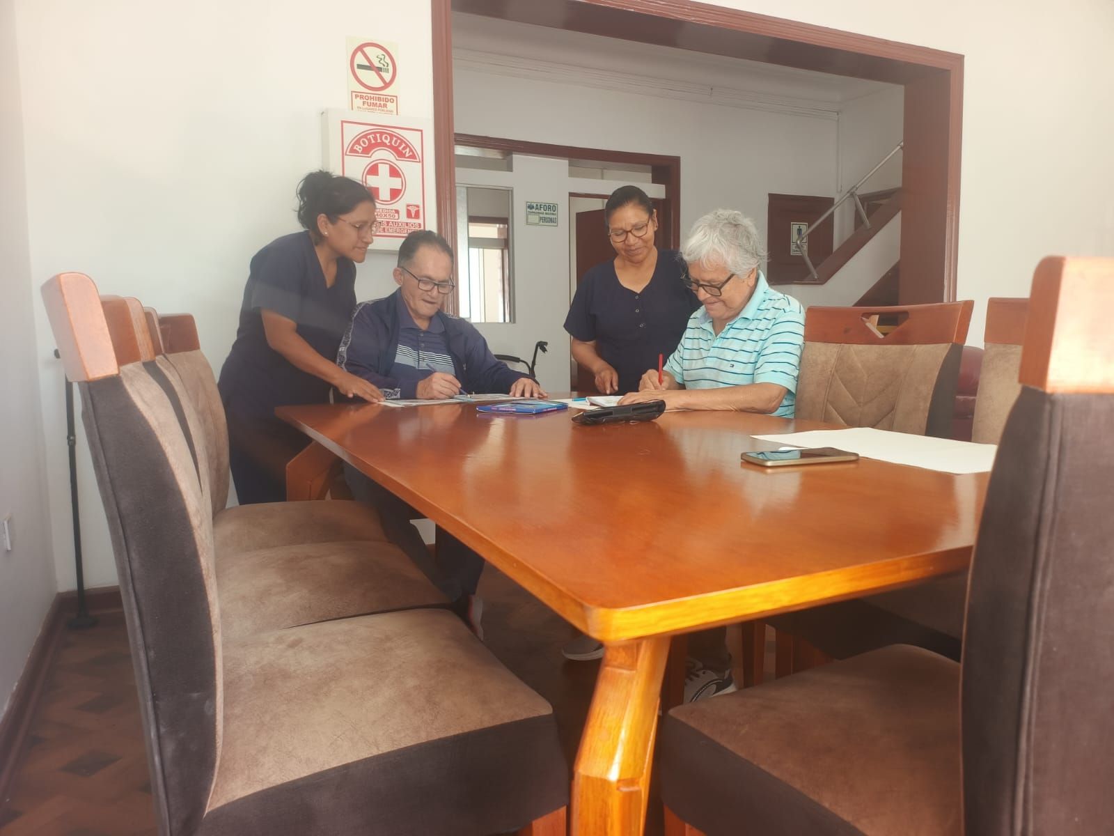 Cuatro personas están sentadas en una acogedora sala de estar, charlando alrededor de una mesa
