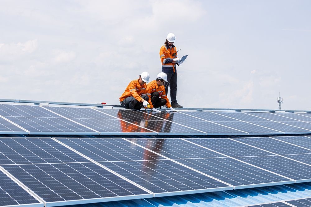 A person installing a solar panel on a gray corrugated metal roof.