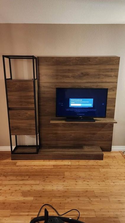a television is mounted on a wooden wall in a living room .