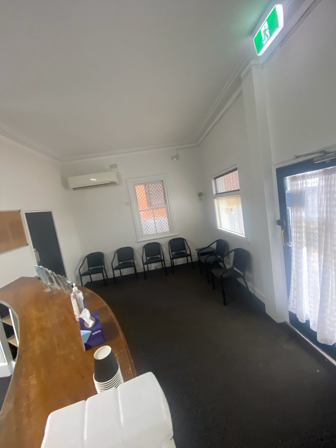 Empty Office Waiting Area With Chairs, Desk, and a Lit Exit Sign — Robert Seeliger Painter And Decorator in Parkes, NSW