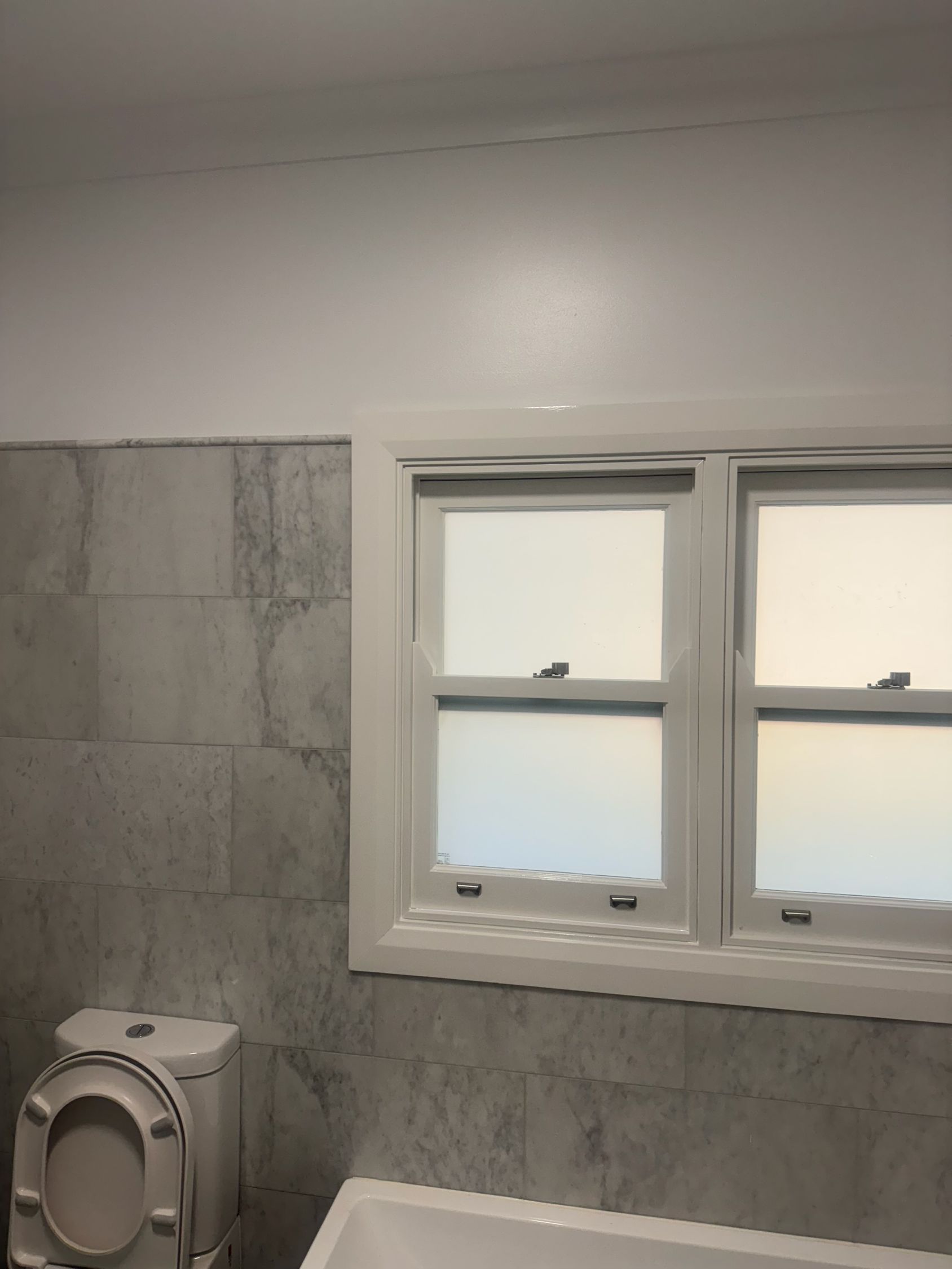 Bathroom With Gray Tiled Walls, a White Window, and a Toilet — Robert Seeliger Painter And Decorator in Dubbo, NSW