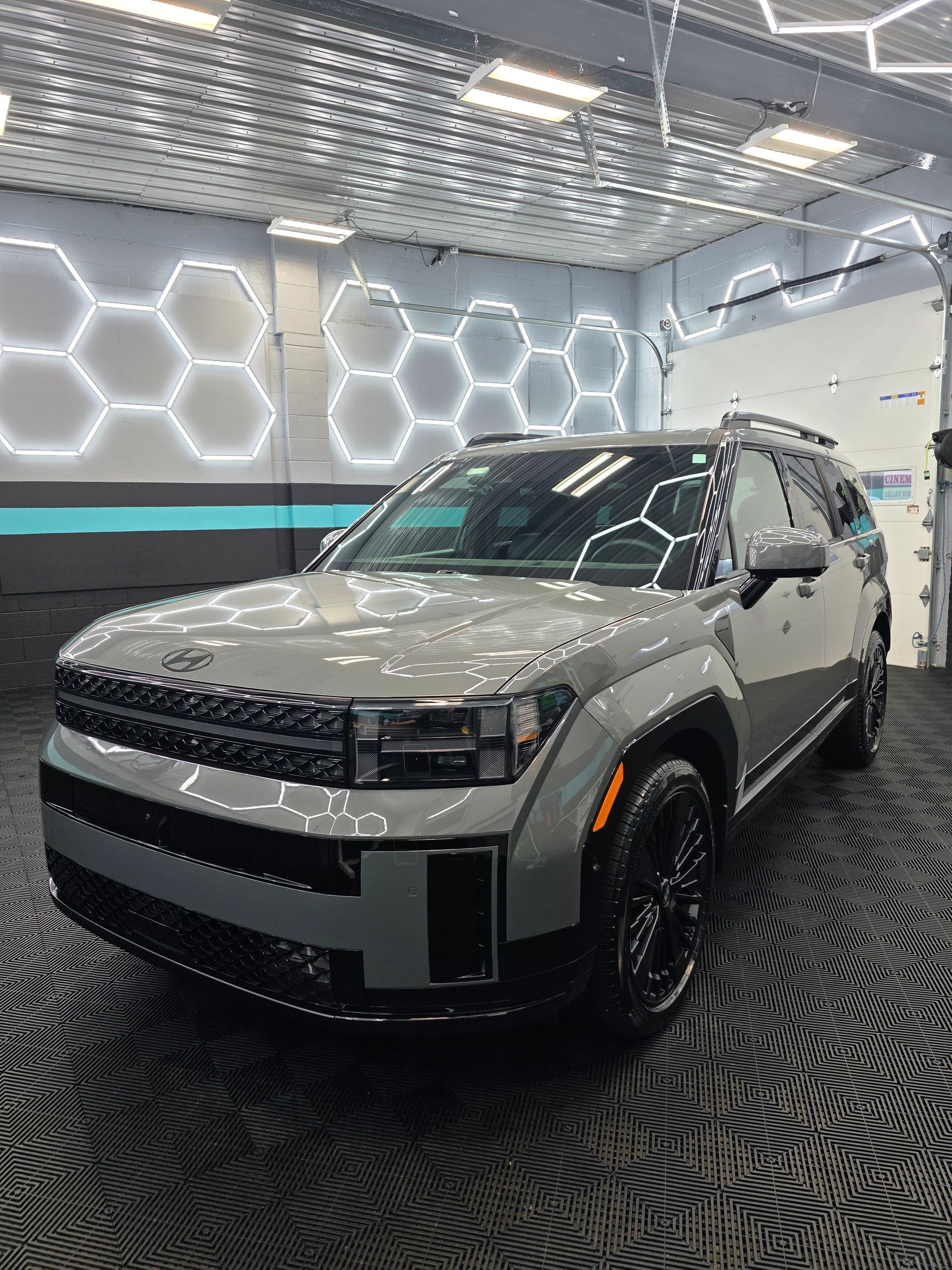 Gray SUV in a showroom with hexagonal wall lights and patterned black floor.