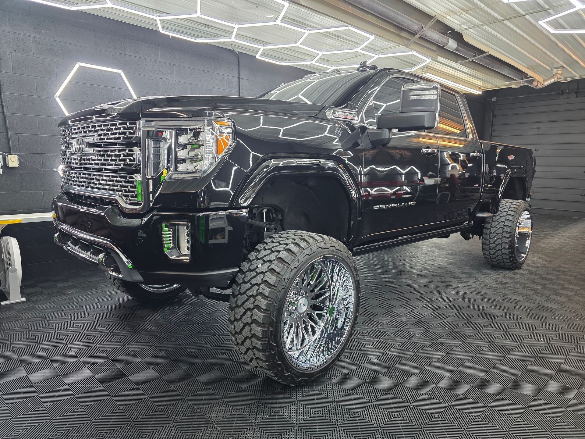 Black lifted pickup truck with chrome accents in a showroom, viewed from the front-left.