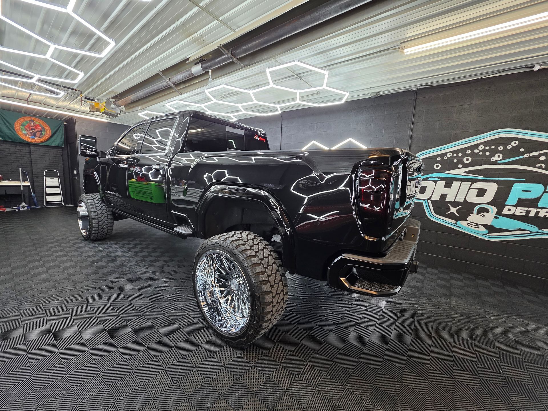 Custom black lifted truck with chrome wheels in a showroom under bright geometric lights