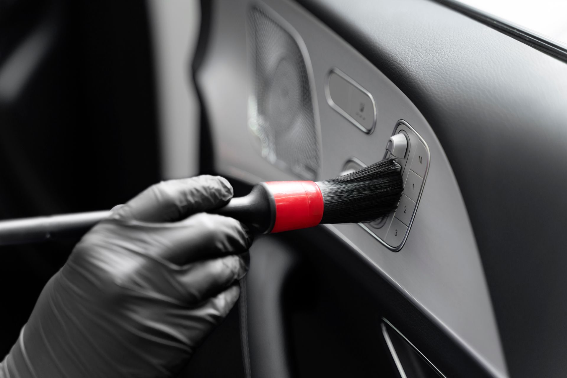 A person is cleaning the interior of a car with a brush.