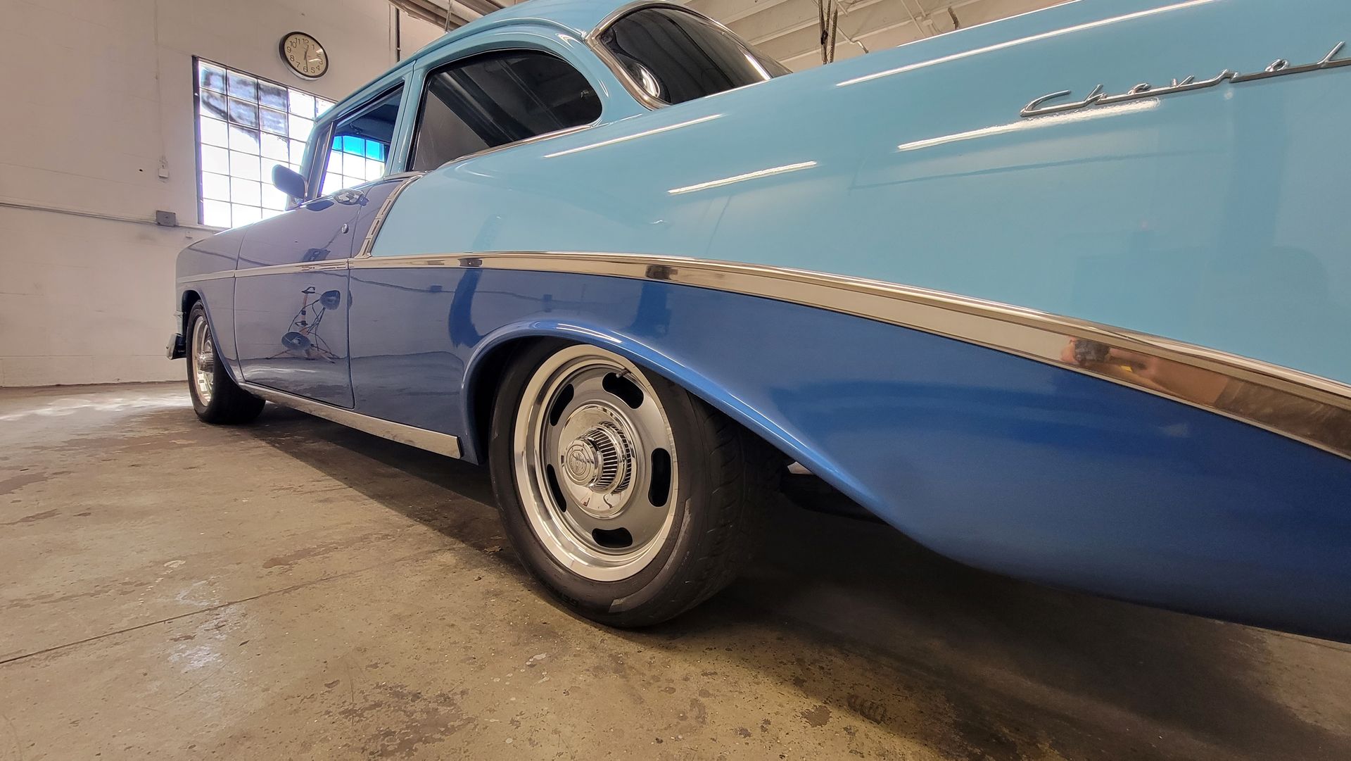 Low-angle view of a light blue classic car with a blue lower body in a garage
