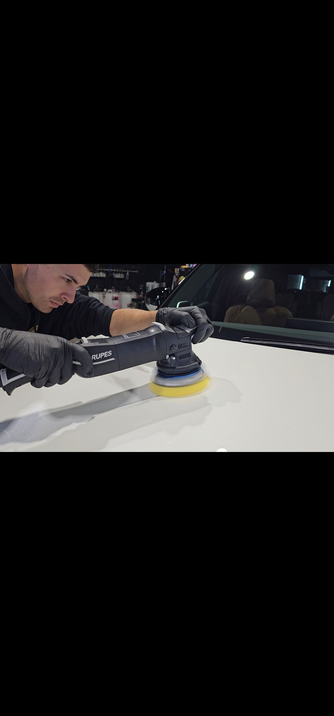 Person using a handheld buffer to polish a white surface at night