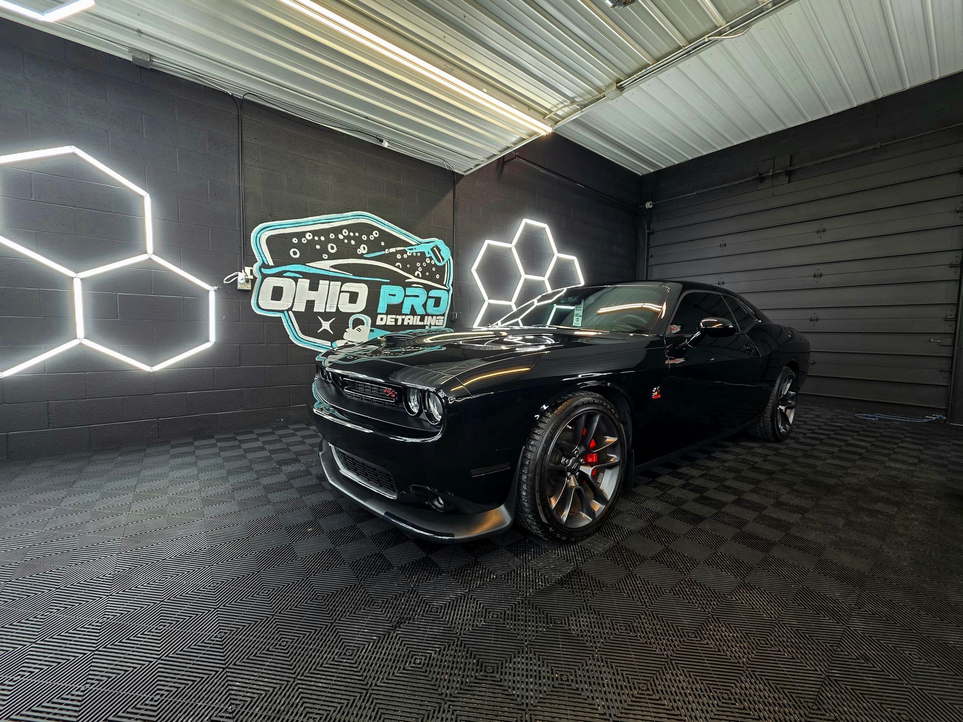 Black sports car in a neon-lit garage with “Ohio Pro” sign and hexagon wall lights