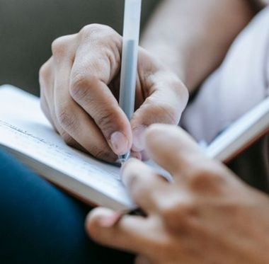 Hand holding biro writing in book