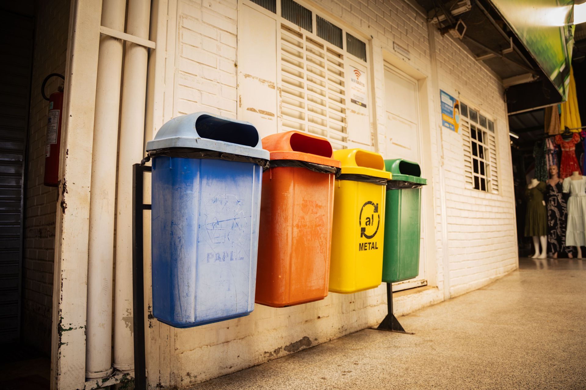 A row of four colourful bins hanging on a wall, in blue, red, yellow and green.