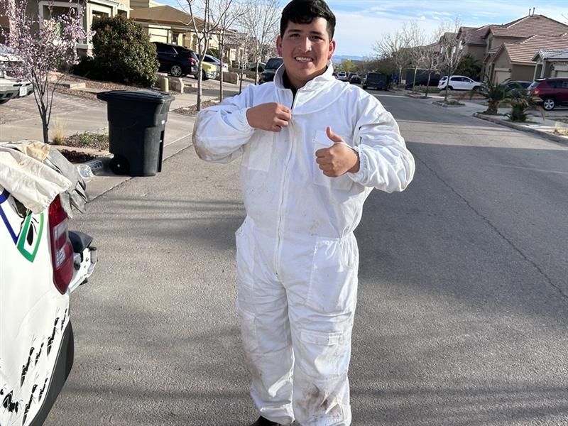 Person in a white protective suit giving two thumbs up on a suburban street.