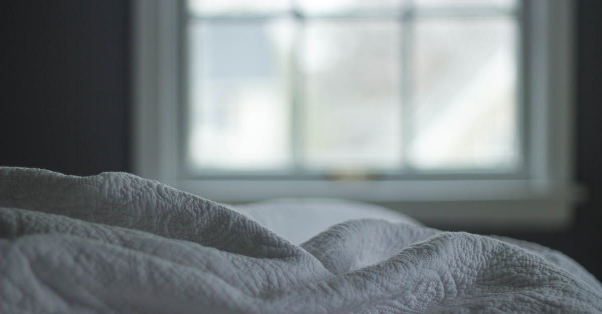 Soft gray blanket on a bed in front of a bright window