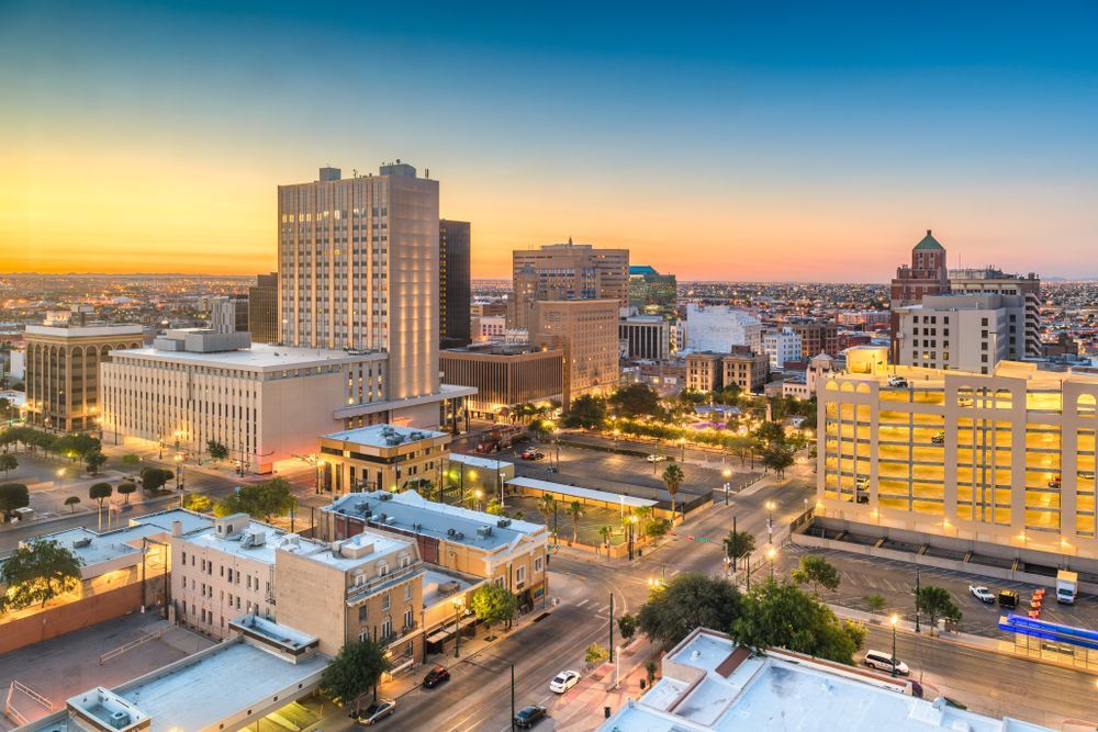 Sunset city skyline with illuminated buildings and streets under a colorful sky