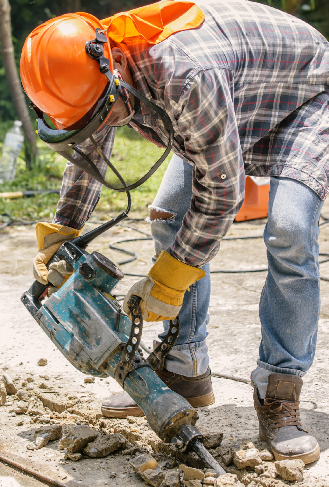 A construction worker is using a hammer to break concrete.
