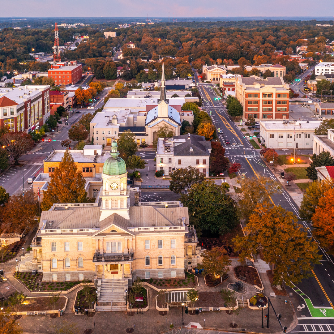An aerial view of a city with a clock tower in the middle of it.