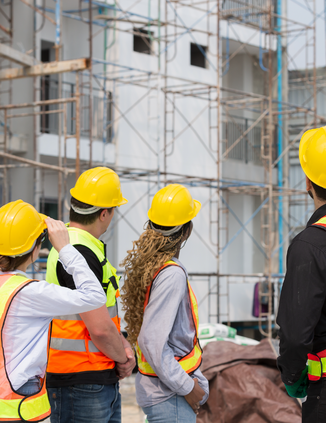 A group of construction workers are standing in front of a building under construction.