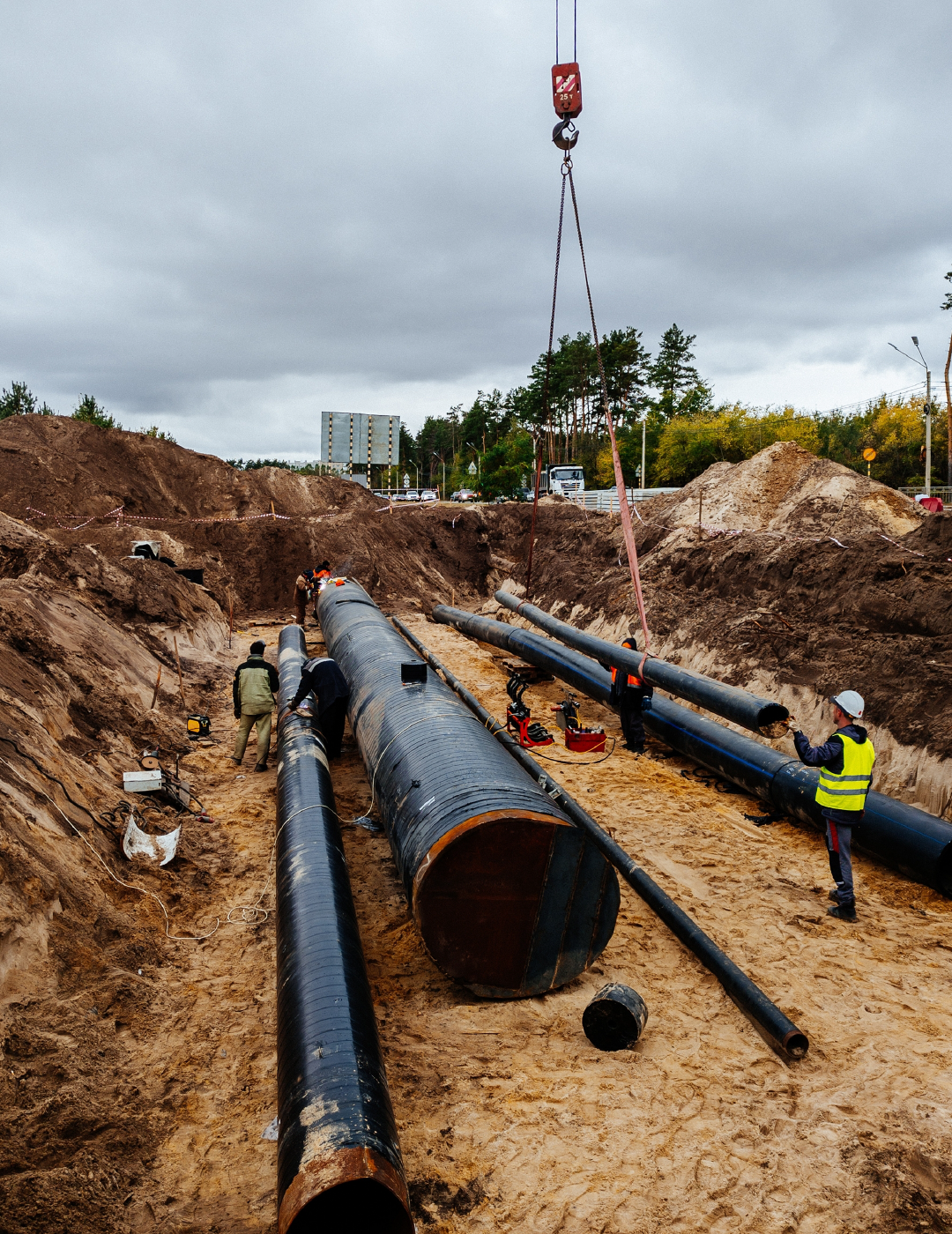 A crane is lifting a large pipe into the ground.