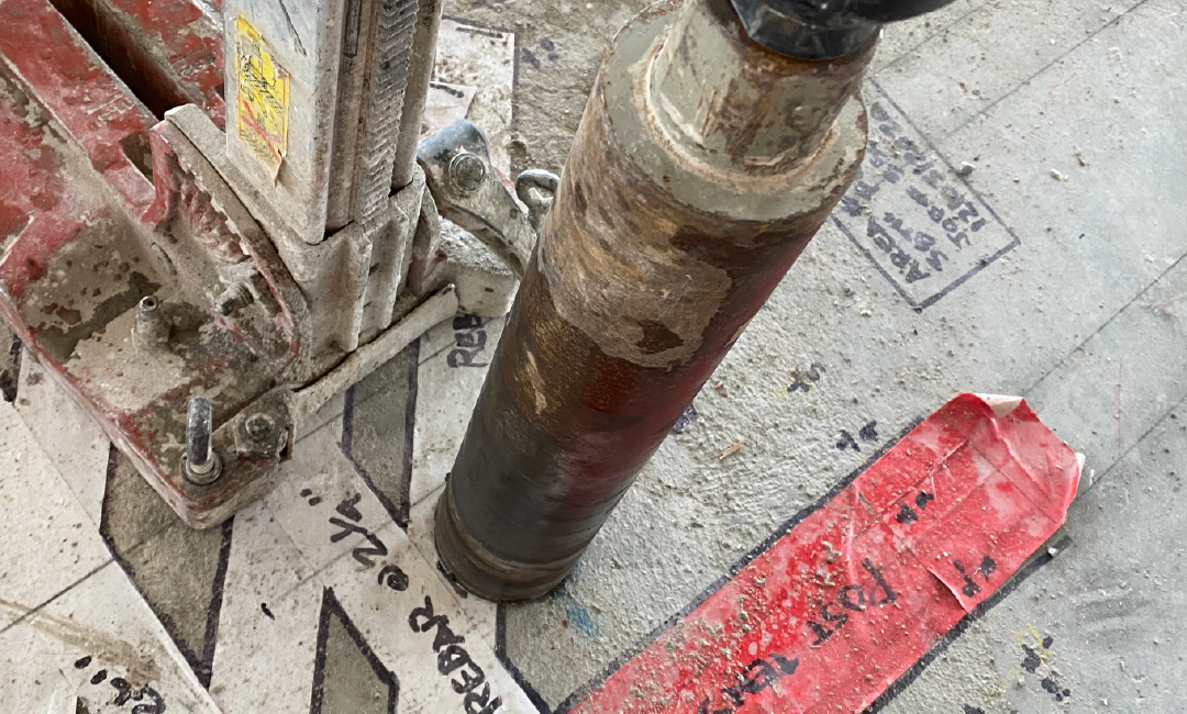 A close up of a drill bit on a concrete surface.