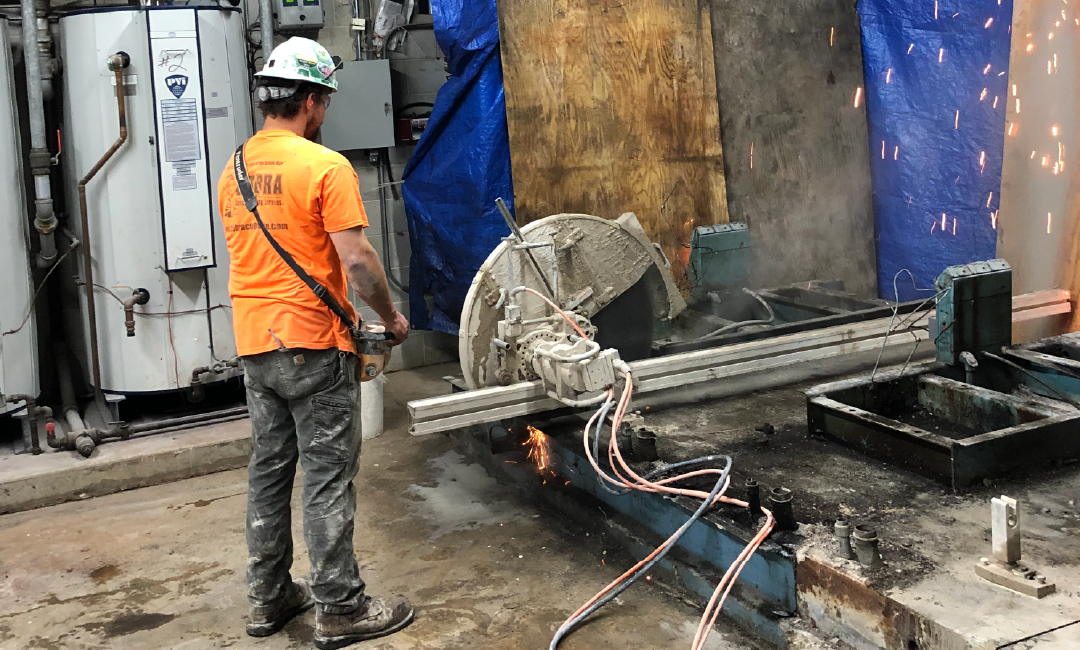 A man is standing in front of a machine that is cutting concrete.