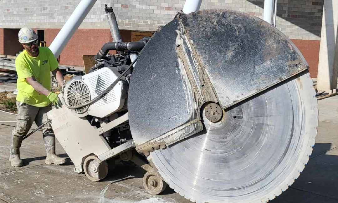 A man is cutting concrete with a large circular saw.