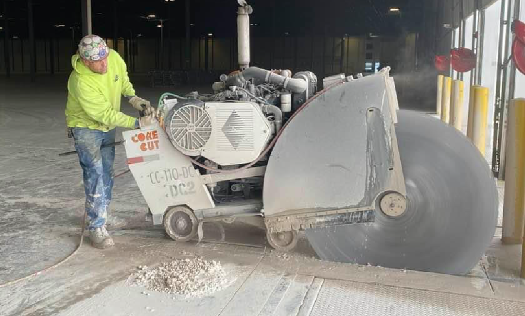 A man is cutting concrete with a circular saw.