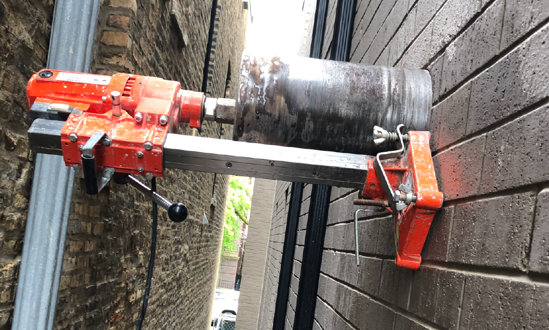A drill is sitting on the side of a brick wall.