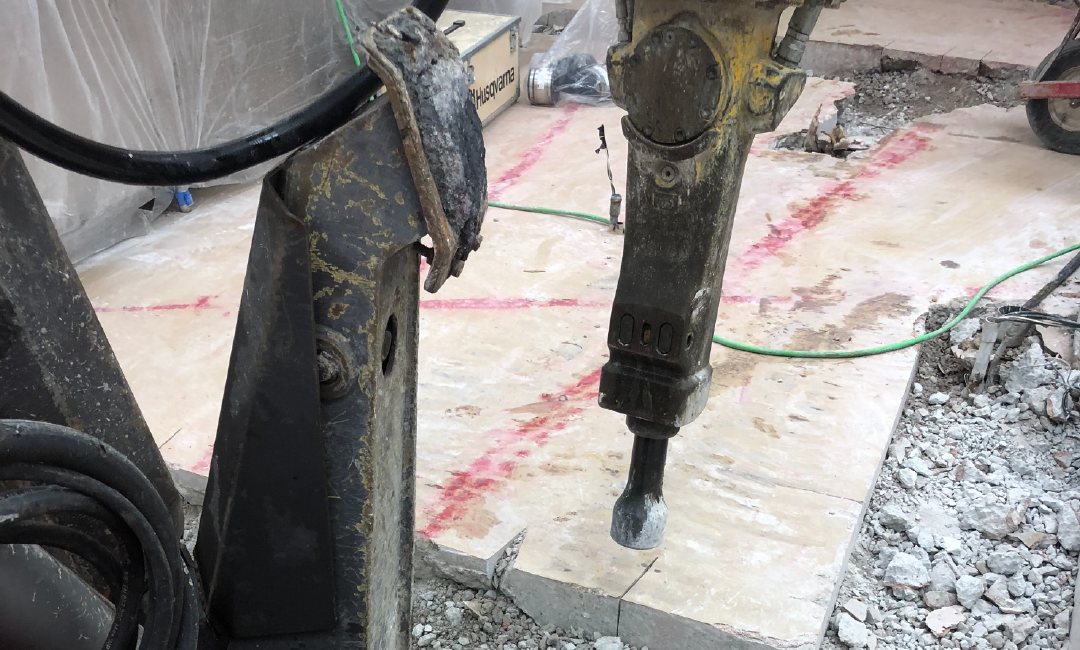 A person is using a hammer to break a concrete slab.