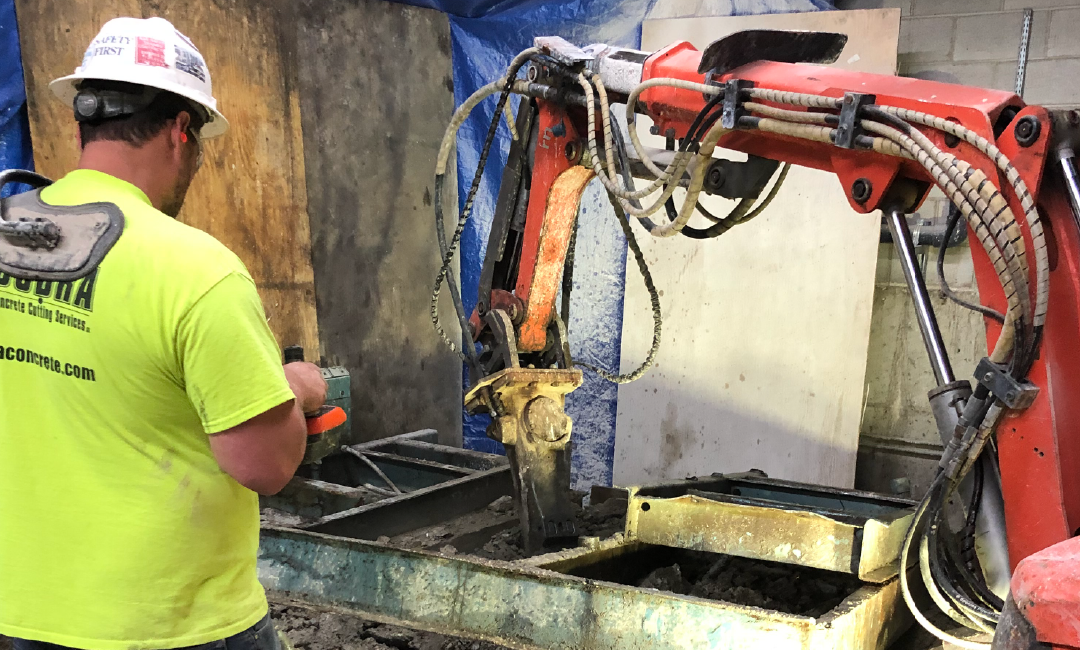 A man in a hard hat is standing next to a robotic arm.
