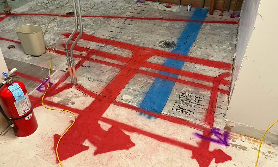 A fire extinguisher is sitting on the floor next to a red and blue tape.
