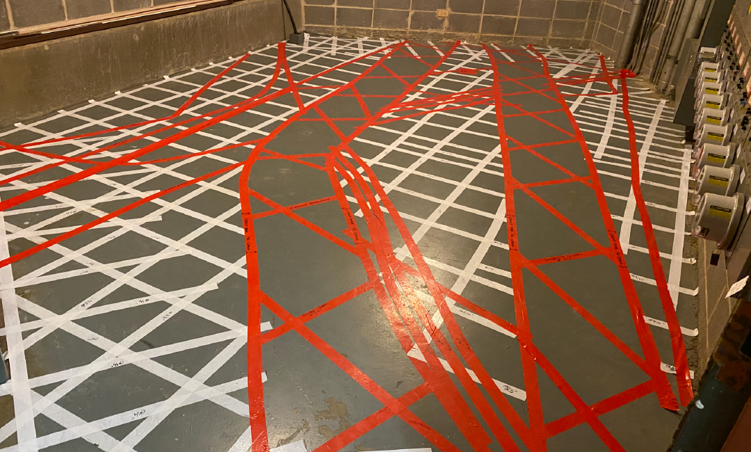 A gray floor with red and white tape on it.