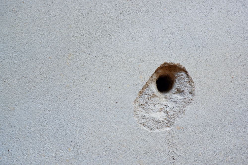 A hole in a white wall with a black hole in the middle.