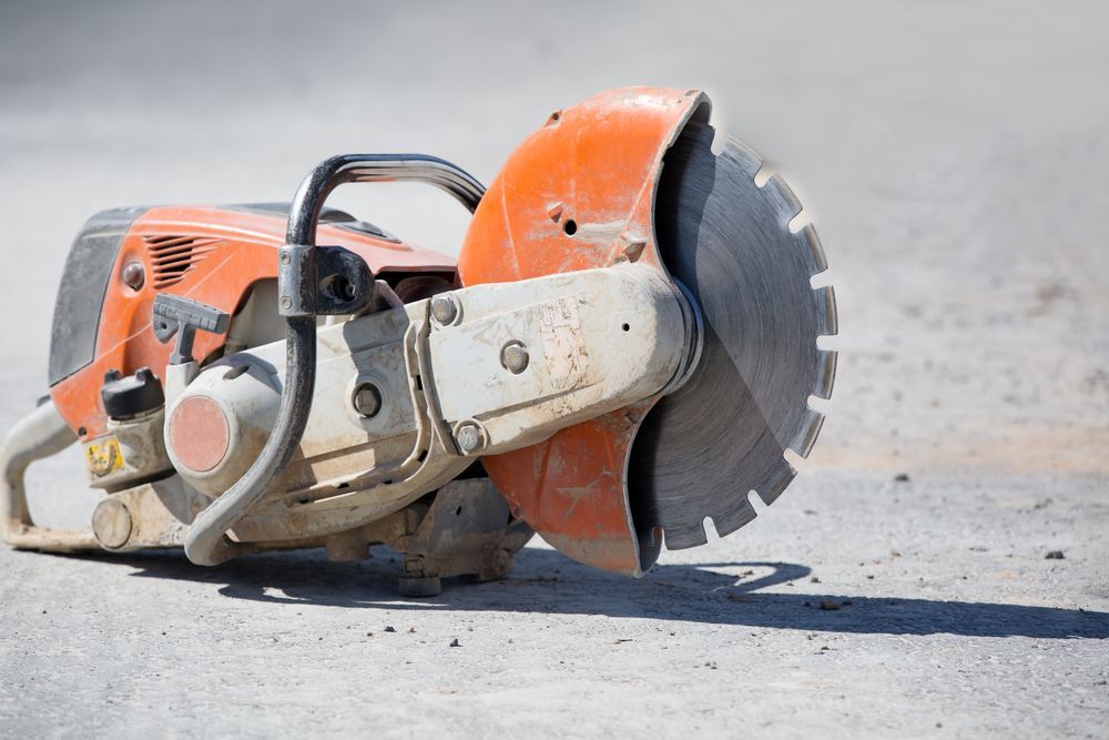 A circular saw is sitting on the ground on a construction site.