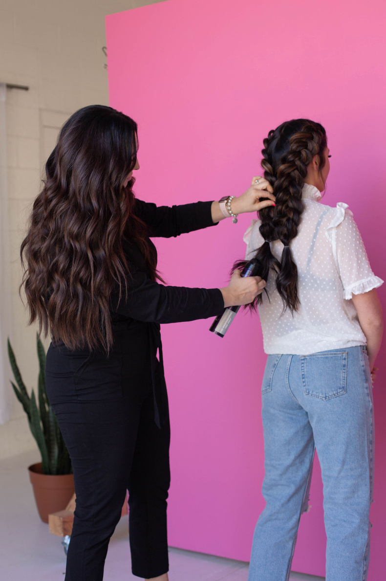 A woman is getting her hair done by a hairdresser in a salon.