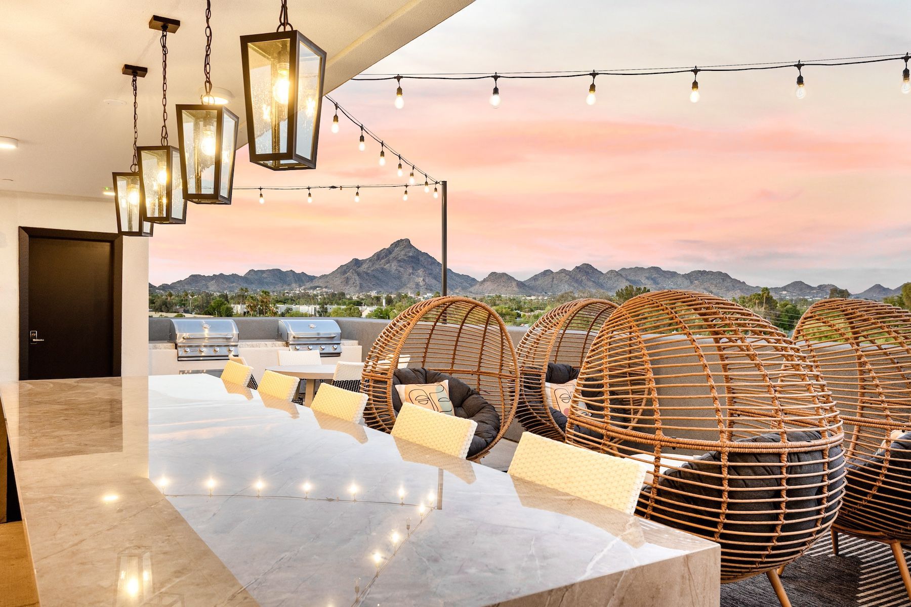 Rooftop lounge area with grills, seating, and mountain views at sunset  at Echo Biltmore in Phoenix AZ.