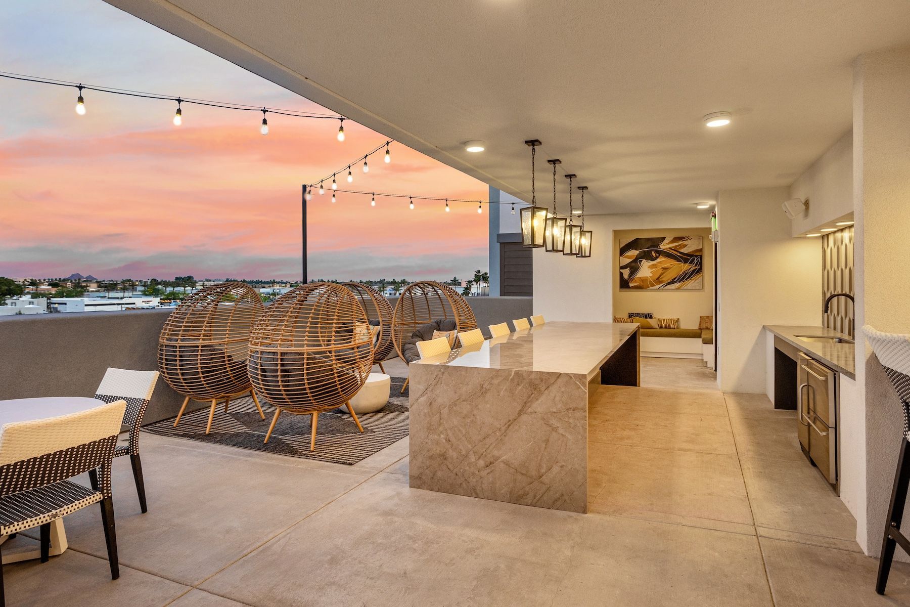 Outdoor lounge area with string lights, woven chairs, and a long communal table at Echo Biltmore in Phoenix AZ.