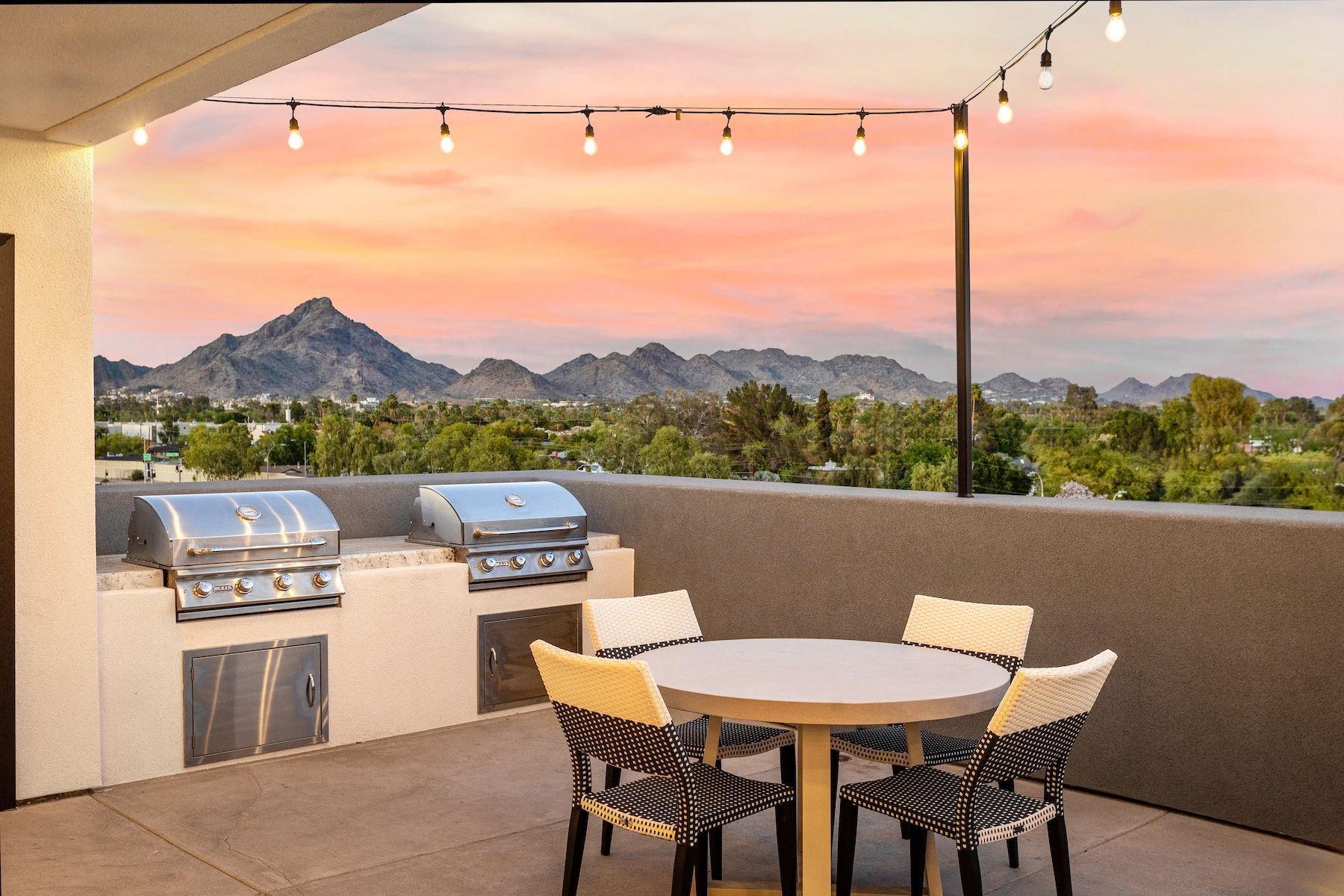 Outdoor patio with grills and seating area with mountain view at sunset at Echo Biltmore in Phoenix AZ.