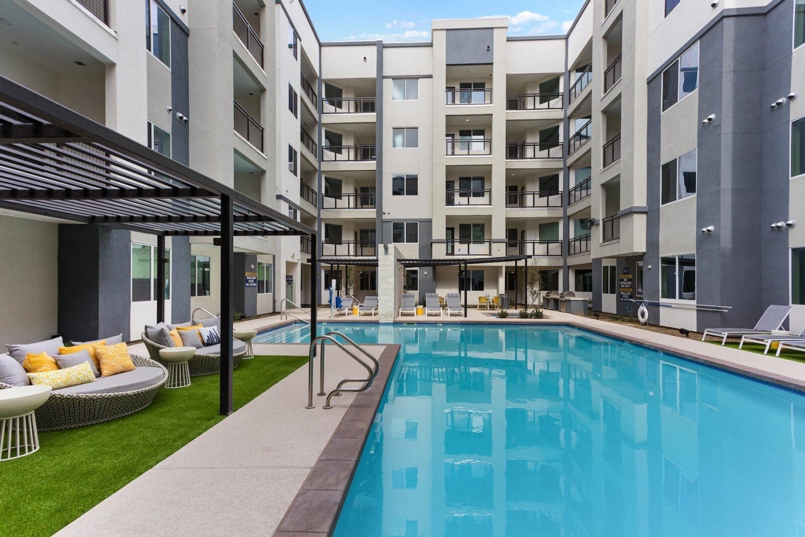 Outdoor swimming pool and lounge area with building in background at Echo Biltmore in Phoenix AZ.