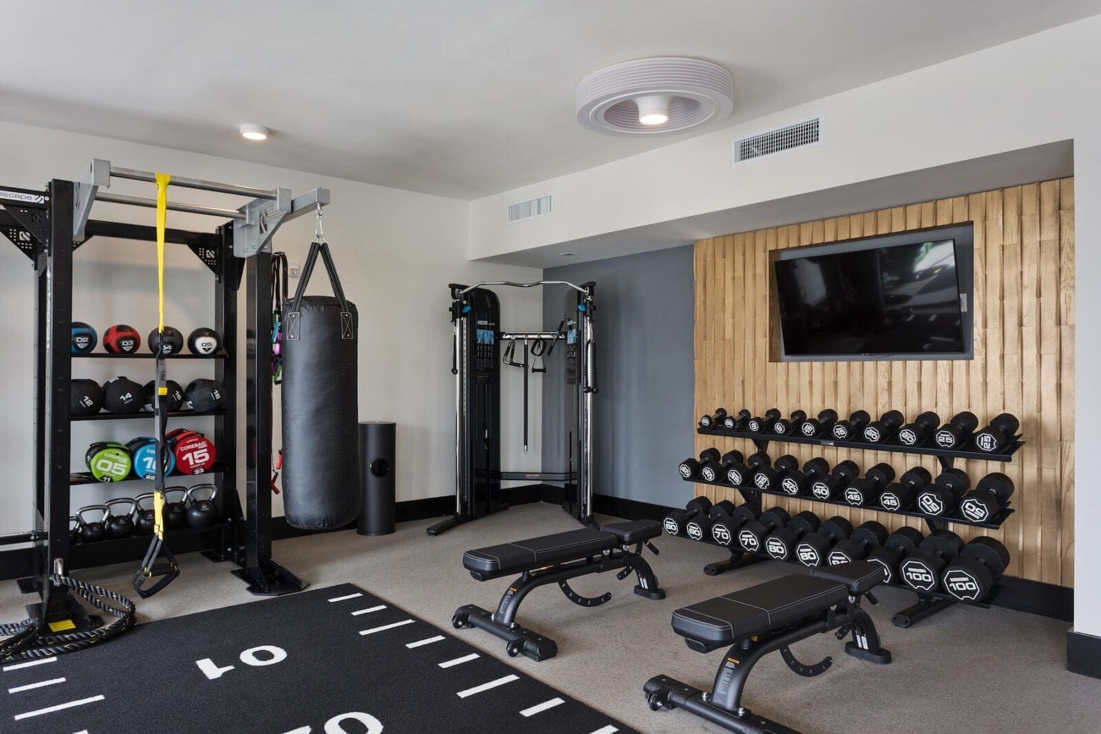 Fully equipped gym with weight racks, punching bag, and exercise benches at Echo Biltmore in Phoenix AZ.