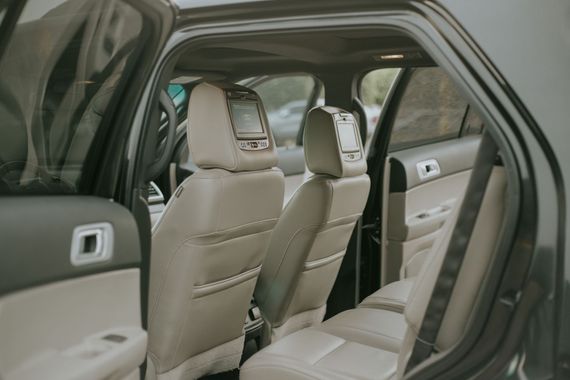 Beige leather car interior with rear and front seats visible through the open door