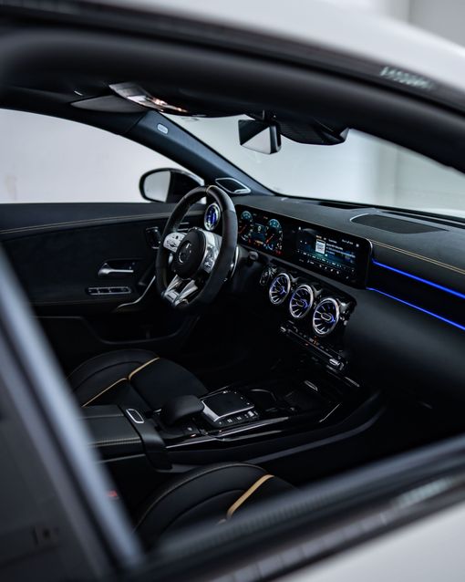 Luxury car interior with black leather seats, digital dashboard, and blue ambient lighting