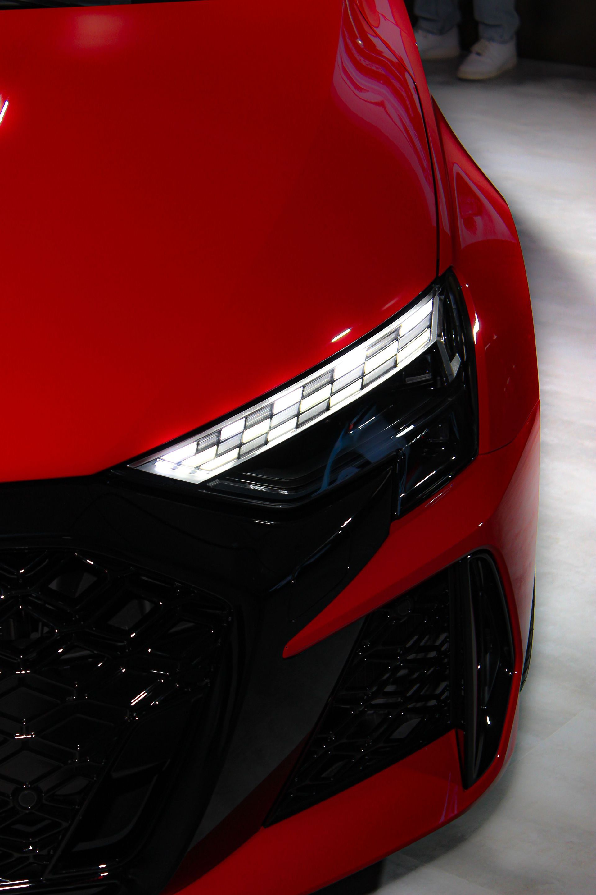 Close-up of a red sports car front headlight and grille detail