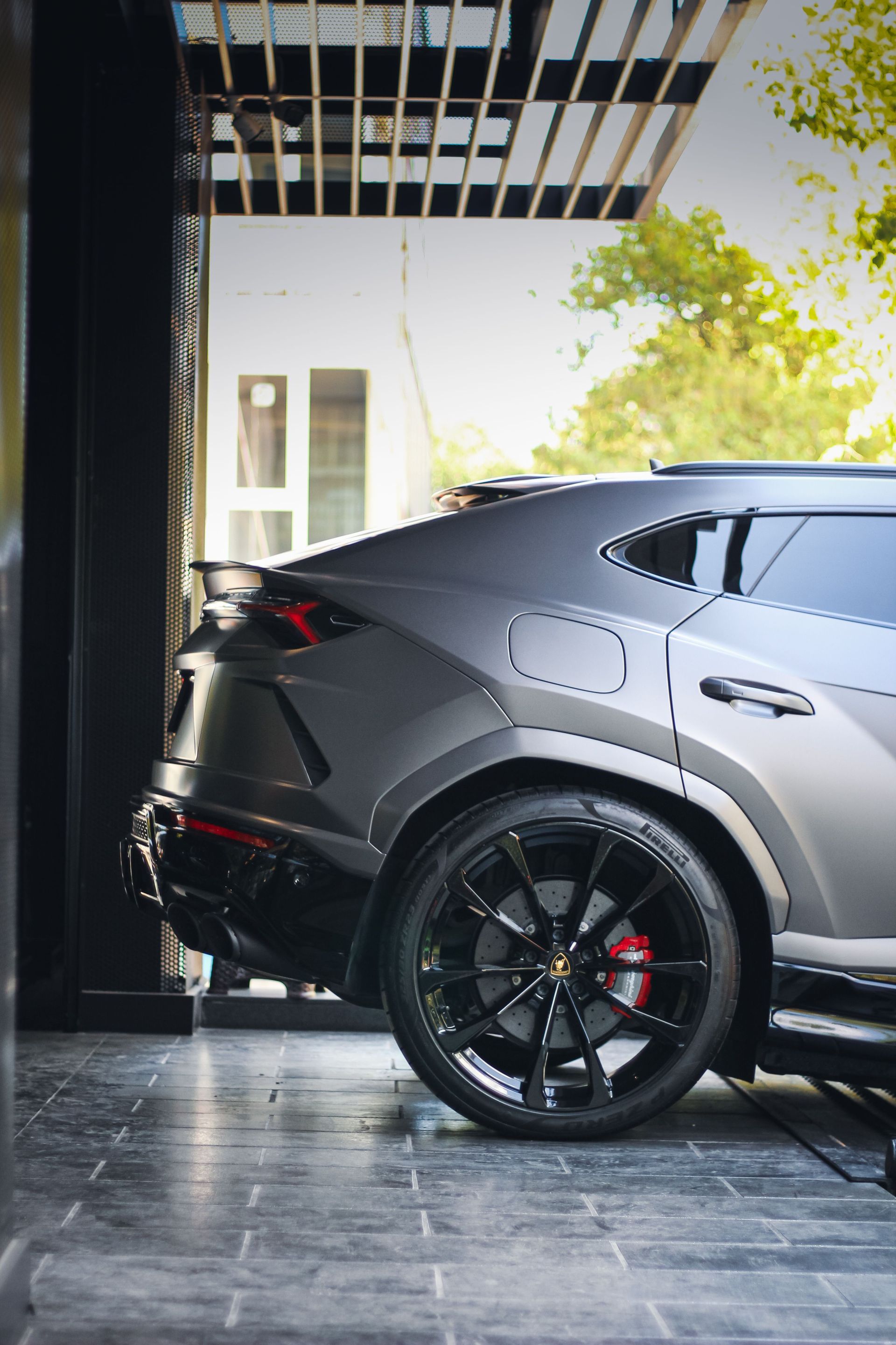 Black luxury SUV parked in a modern driveway, showing the rear side and wheel.