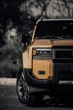 Front view of a black and tan SUV parked outdoors, with a dark blurred background.