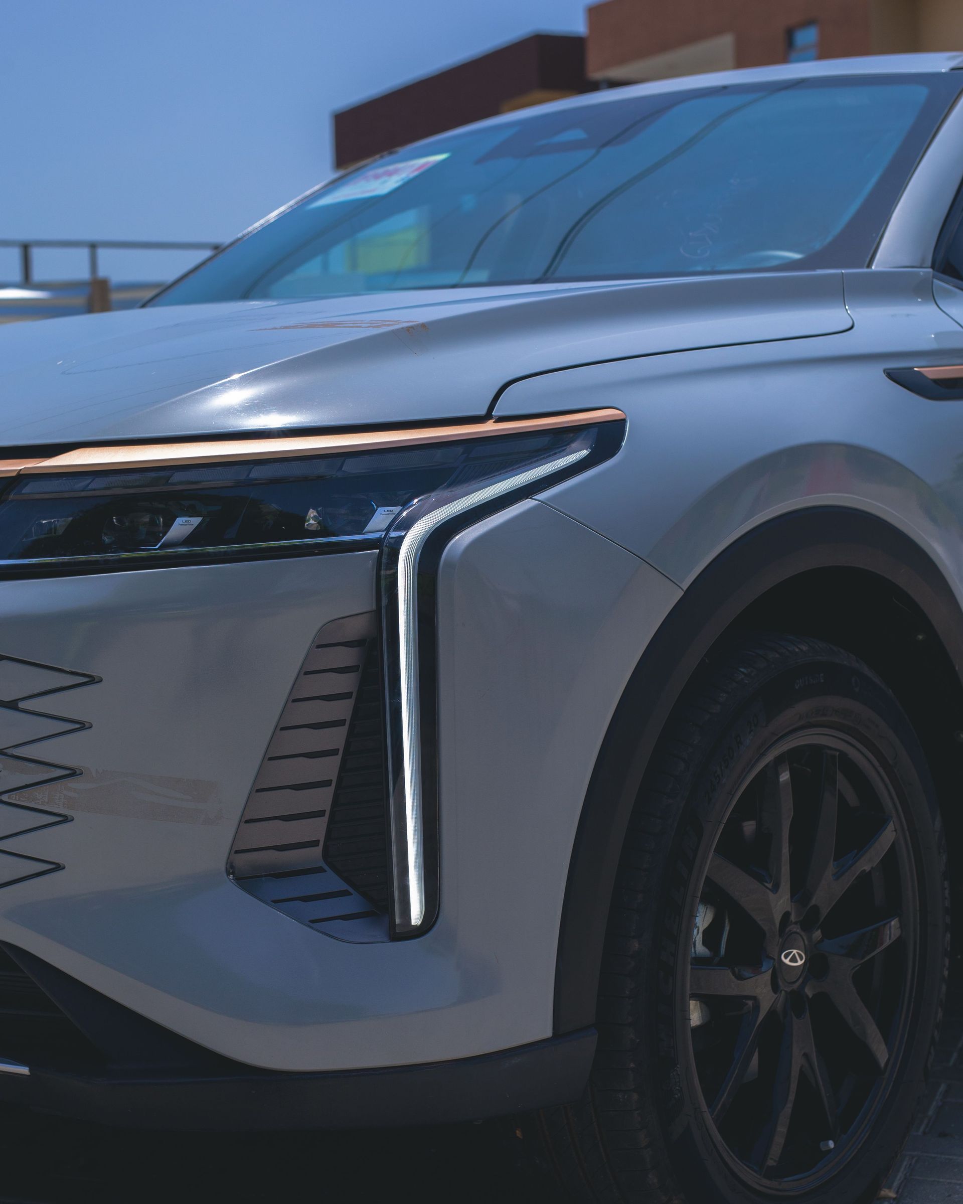 Close-up of a silver SUV’s front end with vertical LED lights parked outdoors.