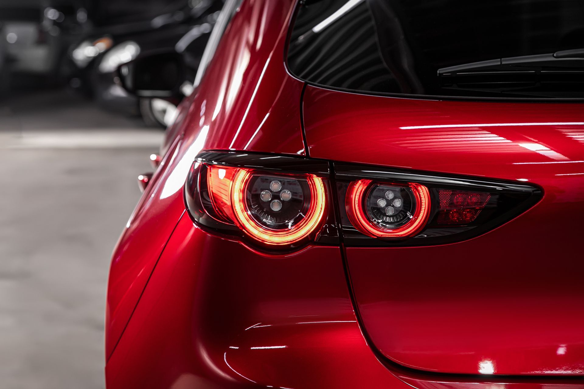 Rear of a red car with illuminated circular taillights in a parking garage
